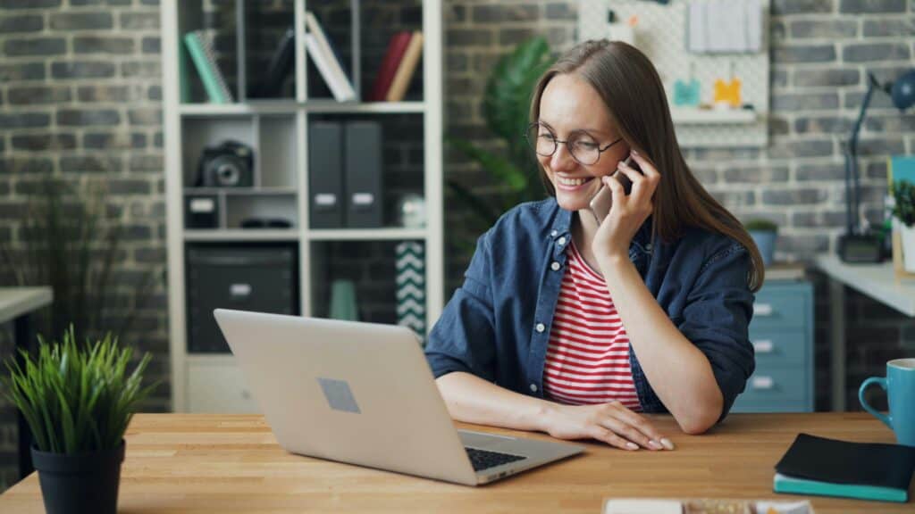 Frau sitzt am Laptop und telefoniert